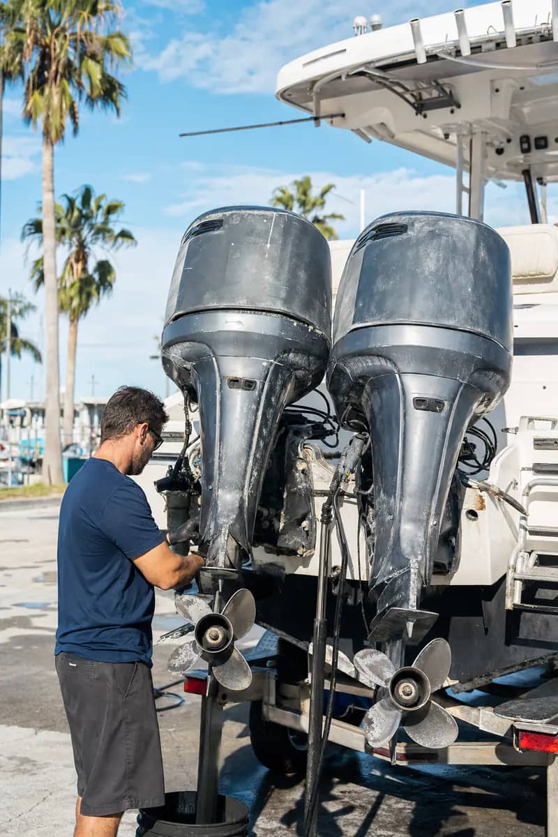 Technician next to triple outboard engines in a Miami boatyard